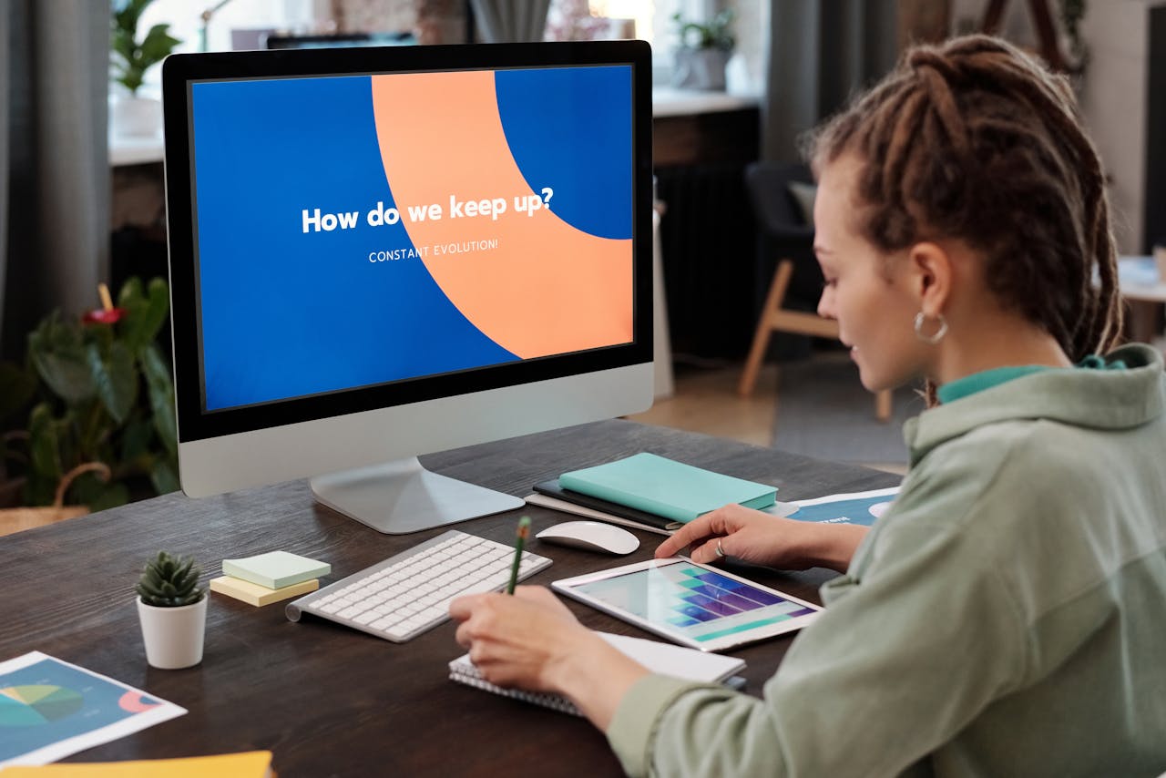Woman engaging in creative digital strategy planning on a tablet and computer at home office.